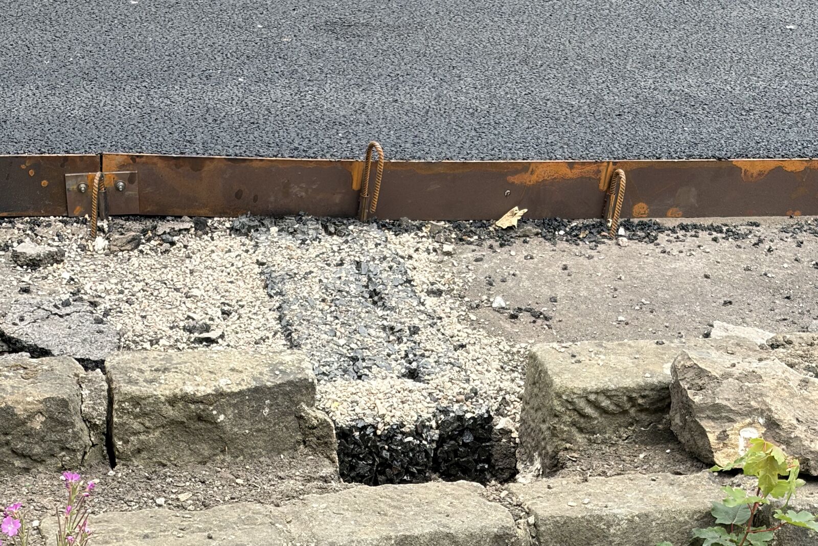 Grip Strip passing through the retaining wall coping with the new porous asphalt terrace behind