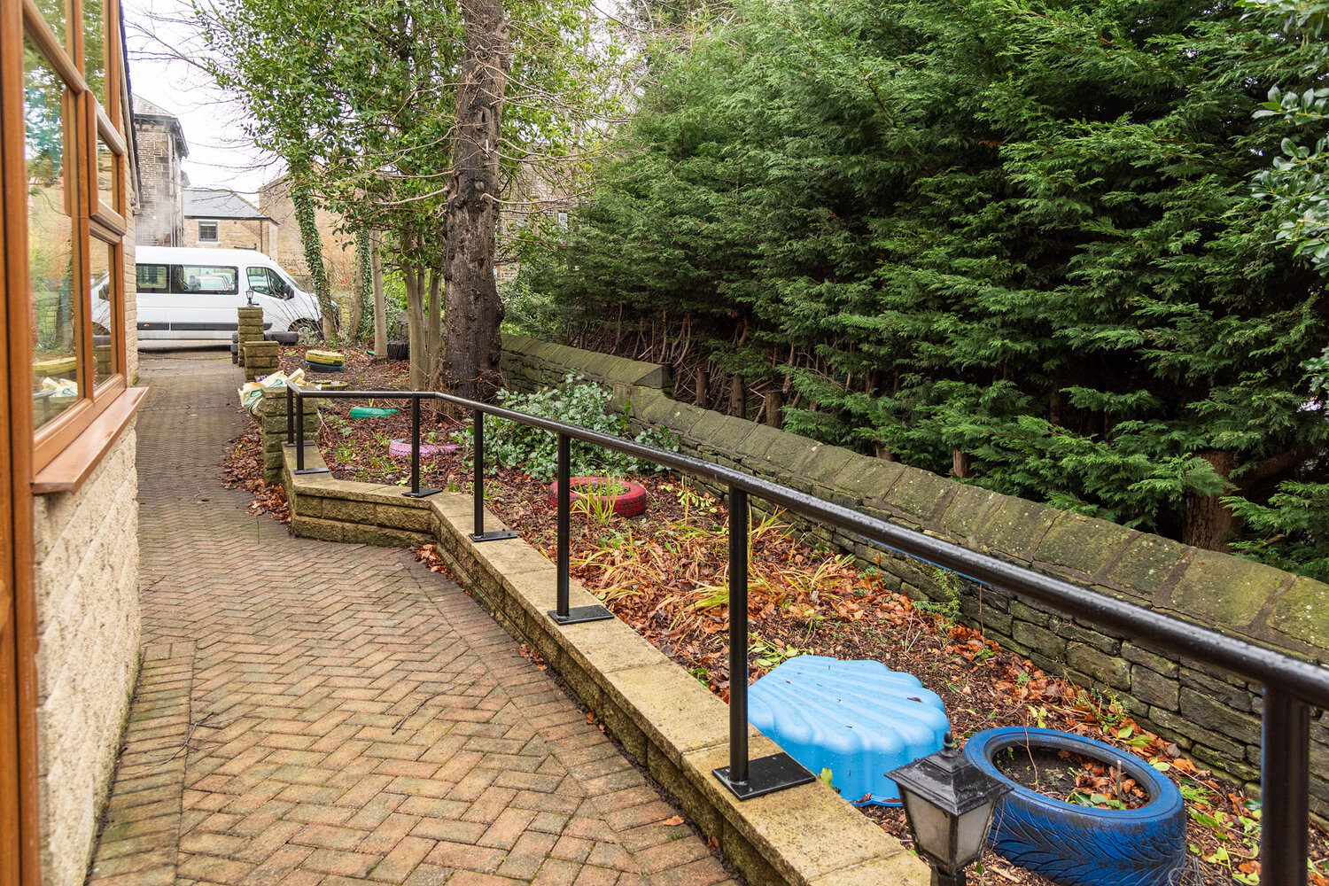 Overgrown garden area before installation with uneven brick path