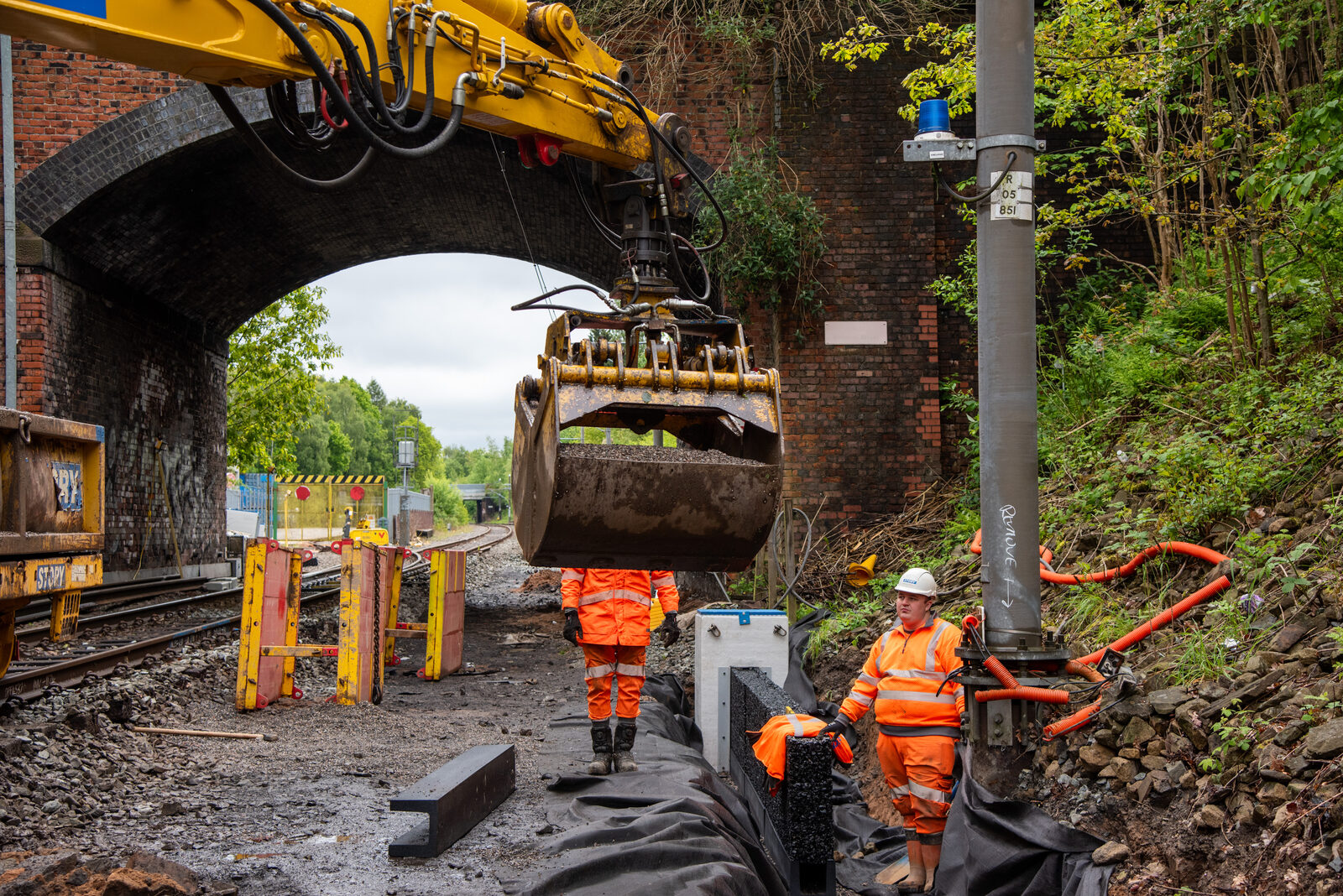 Rail crane placing aggregate over the Rosehill Drainage System beneath a bridge at Newton Heath