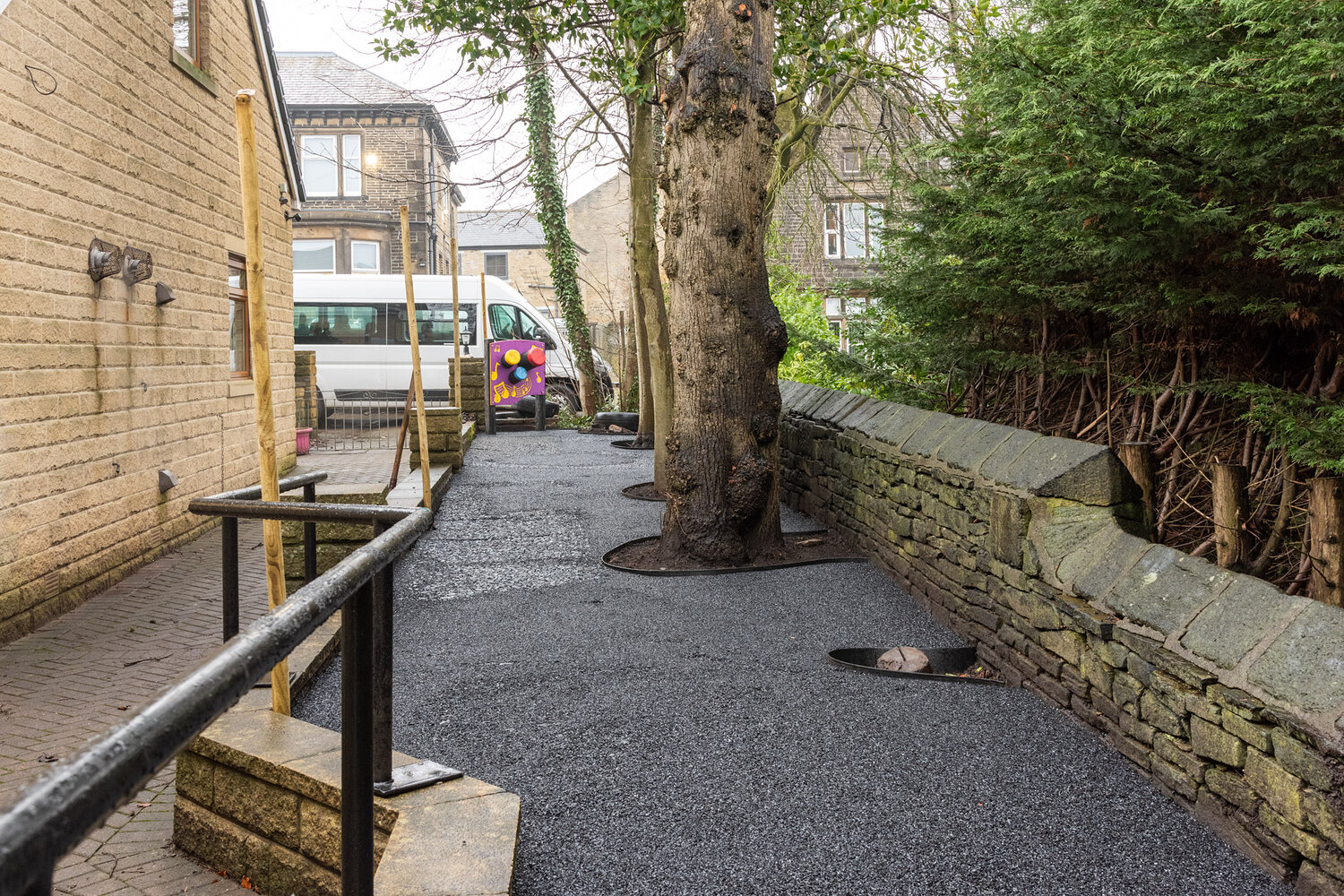 Chemin en base SBR terminé avec rampes accessibles autour d'un arbre mature